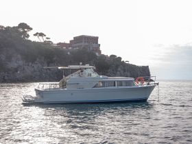 A beautiful yacht glides through calm waters, showcasing its elegant design against a scenic coastal backdrop.