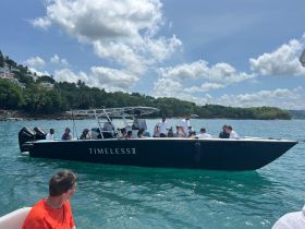 A lively group enjoys a day on the water aboard the TIMLESS II, showcasing the fun and camaraderie of a boat trip in beautiful surroundings.