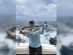 An angler proudly displays a large tuna catch while out on the ocean, showcasing the thrill of deep-sea fishing adventures.