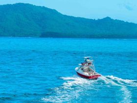A vibrant boat cruises through the turquoise waters, perfect for fishing adventures or exploring coastal destinations.