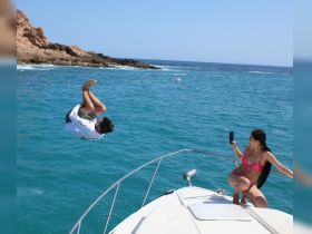 A thrilling moment captured as a man jumps off the boat while a woman records the fun on her phone — perfect for adventurous summer outings on the water.