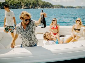A lively group enjoys a fun day on the water, celebrating with drinks aboard a boat — perfect for summer outings and memorable gatherings.