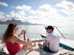 A couple enjoys a serene moment on a boat, capturing the stunning scenery with their camera. Perfect for romantic getaways and scenic boat trips.