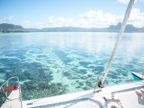 A stunning view from the deck of a catamaran, showcasing crystal-clear waters and vibrant coral reefs — perfect for exploring marine life and enjoying serene sailing experiences.