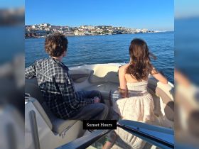 A couple enjoys a serene sunset view from their boat, creating a romantic atmosphere perfect for evening cruises along the waterfront.