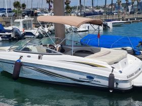 A sleek speedboat docked in a marina, showcasing its elegant design and inviting seating area — perfect for a day on the water.