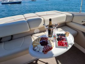A beautifully arranged charcuterie platter with fruits and champagne on a boat, perfect for a luxurious day on the water.