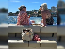 Two friends enjoy cocktails on a sunny day aboard a pontoon boat, making for a perfect celebration on the water.