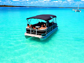 A group enjoys a relaxing day on a pontoon boat in stunning turquoise waters, perfect for soaking up the sun and enjoying the beautiful scenery.