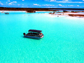 Aerial view of a pontoon boat anchored in stunning turquoise waters, with people enjoying a sandbar stop — a perfect setting for a fun day on the water.
