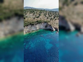A stunning aerial view of a secluded coastline with crystal-clear waters, showcasing a small boat anchored near the shore — perfect for exploring hidden gems and enjoying nature's beauty.
