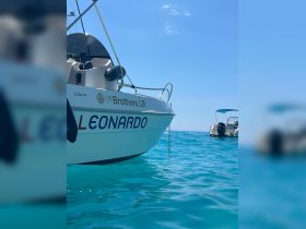 A close-up view of the 'LEONARDO' boat, showcasing its sleek design against the vibrant turquoise waters, perfect for a day of adventure on the sea.