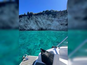 A stunning view of a boat navigating through crystal-clear waters, with a dramatic cliffside backdrop, perfect for exploring coastal landscapes.