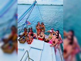 A lively group of friends enjoys a fun day on a boat, celebrating together with drinks and laughter under the sun — perfect for a memorable outing.
