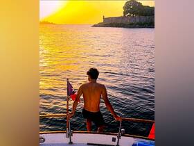 A young boy enjoys a stunning sunset view from the bow of a boat, capturing the essence of adventure on the water.