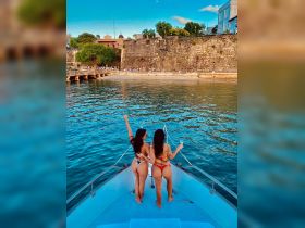 Two friends enjoy a vibrant day on the boat, celebrating with drinks and stunning waterfront views — perfect for memorable outings and adventures.