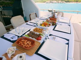 A beautifully arranged dining table on a yacht featuring a variety of gourmet dishes, perfect for enjoying a luxurious meal while cruising on the water.