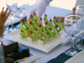 An elegant display of gourmet appetizers featuring creatively arranged cucumber and cherry garnishes, perfect for upscale dining experiences on a boat.