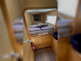 Cozy cabin interior featuring a comfortable bed with pillows and natural light streaming in through the window, perfect for relaxing on a boat.