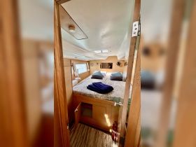 A cozy cabin interior featuring a double bed with decorative pillows and a neatly arranged space, perfect for relaxing on a boat.