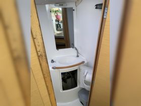 Interior view of a boat bathroom featuring a sink, mirror, and storage space, showcasing the functional design of onboard amenities.