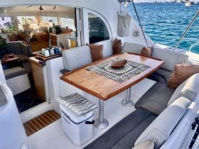 Cozy interior seating area of a boat featuring a wooden dining table and comfortable cushions, perfect for relaxing and enjoying meals while on the water.