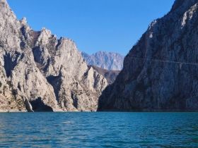 A stunning view of rugged mountains rising above tranquil waters, showcasing the natural beauty of the landscape — perfect for outdoor adventures and scenic boat trips.