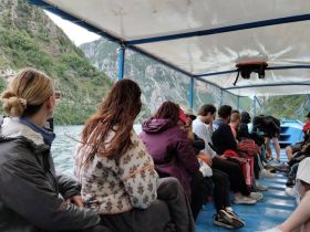 A group of passengers enjoys a scenic boat ride, taking in the lush mountainous landscape — perfect for adventure seekers and nature lovers.