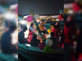 A lively celebration aboard a decorated boat, featuring guests enjoying the festive atmosphere with balloons and flowers — perfect for memorable gatherings on the water.
