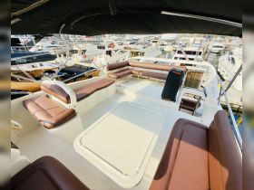 Interior view of a spacious lounge area on a boat, featuring comfortable seating and a table, perfect for relaxing while enjoying the water.