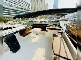 Interior view of a spacious boat cabin featuring comfortable seating and a helm, perfect for relaxing or entertaining while docked.