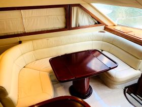 Cozy interior seating area of a boat featuring a stylish lounge and table, perfect for relaxing while enjoying the views on the water.