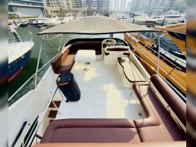 A spacious interior view of a yacht's seating area, featuring comfortable lounge seating and a helm, perfect for relaxing while cruising.