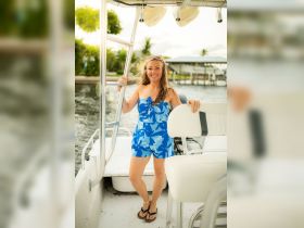 A cheerful woman poses on the deck of a boat, showcasing a fun day on the water — perfect for summer adventures and boating experiences.