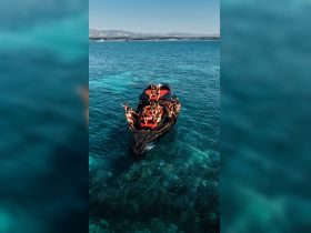 A lively group enjoys a fun day on the water, celebrating aboard a stylish boat with clear turquoise waters as the backdrop.