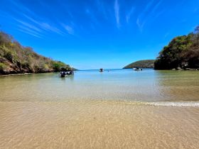 A serene beach scene featuring multiple boats in clear waters, perfect for exploring the beautiful coastline and enjoying a day on the water.