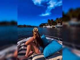 A woman relaxes on the deck of a boat, enjoying the beautiful water scenery and sunny skies — a perfect moment for unwinding on the water.