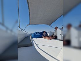 A cozy interior view of a boat's lounge area featuring a child and an adult relaxing on bean bags, perfect for enjoying the serene ocean atmosphere.