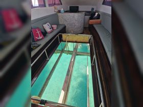 Interior view of a boat cabin featuring comfortable seating and a unique glass-bottom section, allowing for a glimpse of the clear waters below.