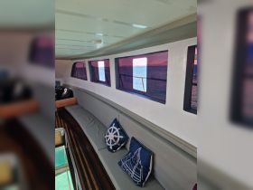 Interior view of a boat cabin featuring comfortable seating and decorative pillows, perfect for relaxing while enjoying the scenic views outside.