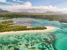 A stunning aerial view of a picturesque island with a sandy beach and vibrant turquoise waters, showcasing the natural beauty of the coastline — perfect for eco tours or island hopping adventures.
