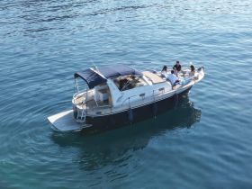 A group enjoys a delightful meal on a boat, surrounded by tranquil waters — perfect for social gatherings and memorable outings.