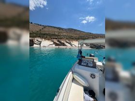 A stunning view from a boat trip showcasing a beautiful beach with people swimming in the turquoise waters — a perfect summer getaway.