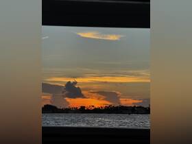 A stunning sunset view over the water, framed by the silhouette of a boat, creating a picturesque scene perfect for evening cruises.