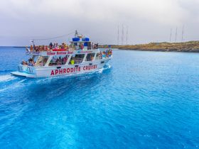 A lively glass bottom boat, Aphrodite Cruises, filled with guests exploring the stunning blue waters — perfect for group adventures and marine sightseeing.