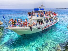 A lively group enjoys a cruise aboard the Aphrodite, surrounded by crystal-clear waters — perfect for a fun day out on the ocean.
