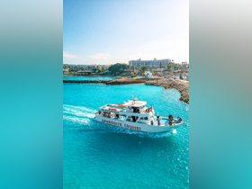 The Aphrodite Cruises boat navigates through stunning turquoise waters, with guests enjoying the scenic views — a perfect choice for ocean adventures.
