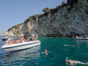 A lively group enjoys a day on the water, swimming and snorkeling near stunning cliffs — perfect for summer adventures and beach outings.