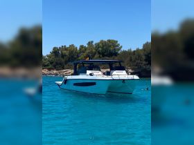 A sleek catamaran anchored in crystal-clear waters, showcasing its modern design against a backdrop of lush greenery — perfect for summer adventures on the water.