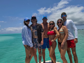 A cheerful group poses together in the crystal-clear waters, capturing a memorable moment during their beach adventure — perfect for celebrating summer fun and friendship.